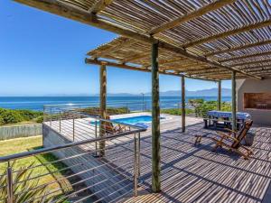 a deck with a view of the ocean and a pool at Whale Sea Cottage in Gansbaai