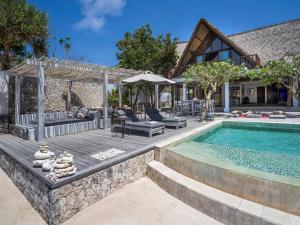 Un patio trasero con piscina y una casa. en Villa Voyage, en Nusa Lembongan