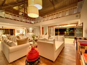 Una sala de estar con sofás blancos y una mesa. en Villa Voyage, en Nusa Lembongan