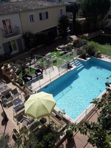 ペルテュイにあるThe Originals City, Hôtel Le Village Provençal, Aix-en-Provence Nord (Inter-Hotel)の傘付きのスイミングプールのオーバーヘッドビュー