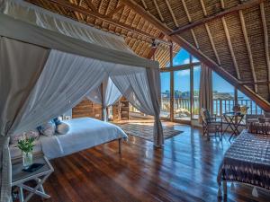 1 dormitorio con cama con dosel y suelo de madera en Villa Voyage, en Nusa Lembongan