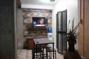 a room with a table and a tv on a brick wall at Peach Haven in Cebu City