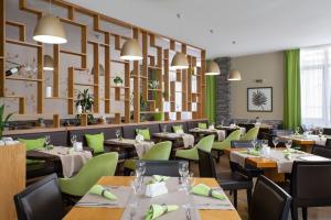 a restaurant with tables and chairs in a room at Golden Tulip Rosa Khutor Hotel in Estosadok