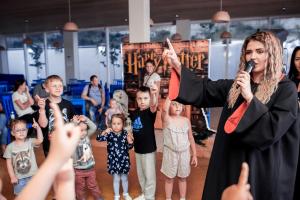 a woman singing into a microphone in front of children at Fioleto Ultra All inclusive Family Resort In Miracleon in Anapa
