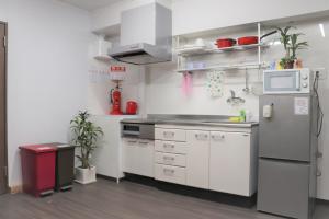 a kitchen with white cabinets and a refrigerator at JAM HOSTEL Hakata Station Front in Fukuoka