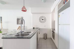a white kitchen with a sink and a refrigerator at Brisbane City Apartments (Tank St CBD) in Brisbane