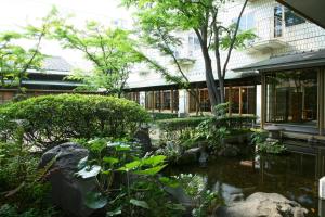 einen Garten mit einem Teich vor einem Gebäude in der Unterkunft Hotel Yokohama Camelot Japan in Yokohama