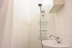 een douche in een wit betegelde badkamer met een wastafel bij Sanders Park - One-Bedroom Apartment Close to the Metro Station in Kopenhagen