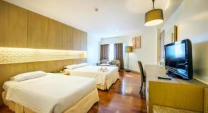 a hotel room with two beds and a flat screen tv at Jomtien Palm Beach Hotel and Resort - SHA Extra Plus in Jomtien Beach