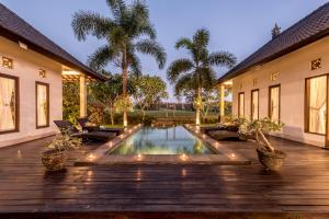 un patio trasero con piscina y terraza de madera en Villa Kubu Agung, en Ubud