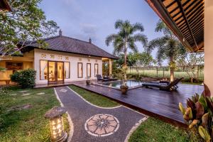 un patio trasero con una terraza de madera y una casa en Villa Kubu Agung, en Ubud