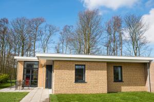 a brick house with a patio and trees in the background at Vakantiewoning Hermelijn in Den Burg