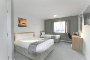 a hotel room with two beds and a desk at Citilodge Wakefield Hotel by Roomsbooked in Wakefield