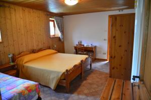 a bedroom with two beds and a table and a door at Agriturismo Pian dei Tass in Barcis