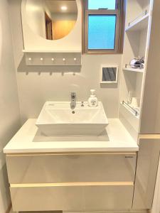 熊本市にあるSUMITSUGU HOUSE Atelierの白い洗面台と鏡のあるバスルーム +42枚の写真