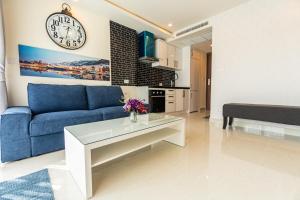 uma sala de estar com um sofá azul e um relógio na parede em Grand Avenue by Fantasea Beach em Pattaya Central