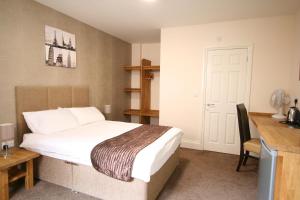a bedroom with a bed, desk, and a lamp at Citilodge Wakefield Hotel by Roomsbooked in Wakefield