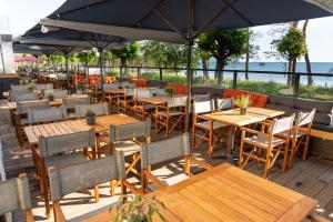ein Restaurant mit Holztischen, Stühlen und einem Sonnenschirm in der Unterkunft Nymphe Strandhotel & Apartments in Binz