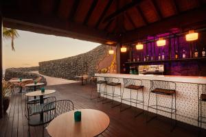 a restaurant with tables and chairs and a stone wall at Secrets Lanzarote Resort & Spa - Adults Only (+18) in Puerto Calero