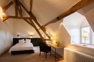 a bedroom with a bed and a desk with a chair at La ferme de Planchevienne in Magny-Cours
