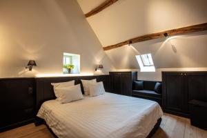 a bedroom with a large bed and a chair at La ferme de Planchevienne in Magny-Cours