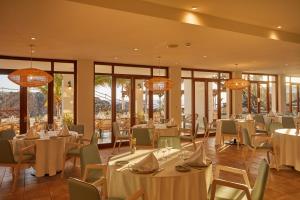 a restaurant with white tables and chairs and windows at Secrets Lanzarote Resort & Spa - Adults Only (+18) in Puerto Calero