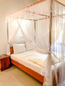 a bedroom with a canopy bed with white curtains at Eden Homestay in Hikkaduwa