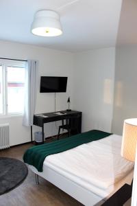een slaapkamer met een bed, een bureau en een televisie bij Rasta Arboga in Arboga