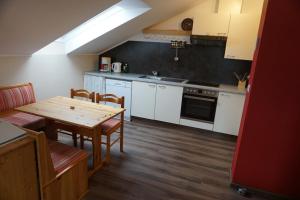 a kitchen with white cabinets and a wooden table with chairs at Gölsenhof - Fam. Büchinger in Wald