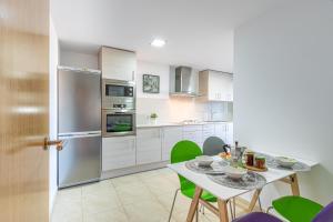 eine Küche mit einem Tisch und grünen Stühlen in der Unterkunft Apart-rent Apartment Cristall Mar 2º 0058 in Empuriabrava