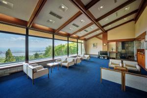 Lake View Inawashiro في Inawashiro: غرفة كبيرة بها كراسي وطاولات ونوافذ كبيرة