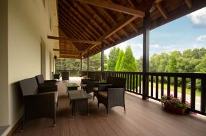 a balcony with chairs and tables and a view of trees at Albergue Piñeiral Fonsagrada in Fonsagrada