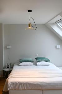 a bedroom with a white bed with green pillows at B&B Korsele 59 in Horebeke