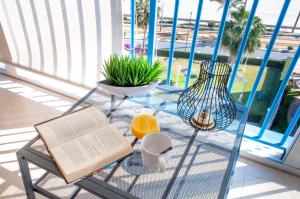 a glass table with an open book and an orange juice at MyFlats Azul in El Campello