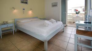 a bedroom with a white bed and two tables at Hotel Ivi in Drios