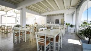 une salle à manger avec des tables et des chaises blanches dans l'établissement Hotel Ivi, à Drios