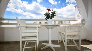a table with chairs and a vase with a flower on it at Hotel Ivi in Drios