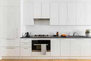 a kitchen with white cabinets and a stove at  Liz by Black Swan - DC Executive Flat in Washington, D.C.