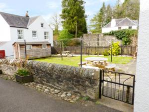 a stone wall with a fence and a picnic table at 8 Cathedral Street in Dunkeld