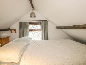 a bedroom with a white bed and a window at Coachman's in Forrabury