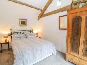 1 dormitorio con 1 cama y armario de madera en Treverbyn Smithy, en Saint Neot