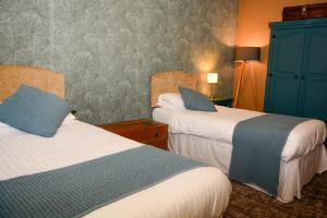 a hotel room with two beds and a blue wall at Plough Inn in Morpeth