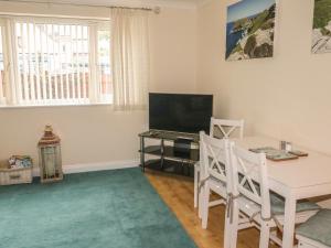 a living room with a table and a television at Kingfisher House in Tintagel