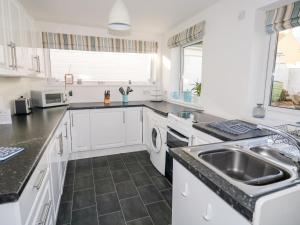 a kitchen with white cabinets and a sink at Waverley in Mevagissey