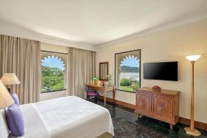 a hotel room with a bed and a desk and a television at Trident Udaipur in Udaipur