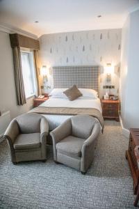 a bedroom with a bed and a pair of chairs at B/W Plus Buxton Lee Wood Hotel in Buxton