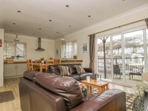 a living room with a leather couch and a table at Rivercrest in Looe