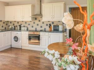 cocina con armarios blancos y mesa de madera en Middle Barn en Launceston