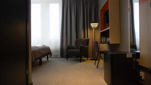 a hotel room with a bedroom with a bed and a desk at First Hotel Central in Norrköping