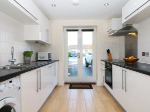 a kitchen with white cabinets and a door to a driveway at 24 Bay Retreat Villas in St Merryn